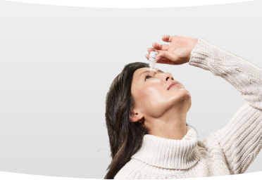 Woman putting VUITYTM prescription eyedrop in eye with VUITYTM bottle and packaging in foreground